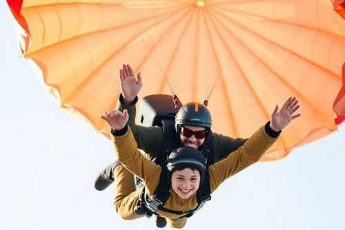 cropped-A-horizontal-image-of-a-boy-and-instructor-tandem-skydiving-warm-autumn-colors-intricate-origami-style-folded-paper-look-geometric-precision-earthy-and-cozy-tones-beautiful-parachute.jpg